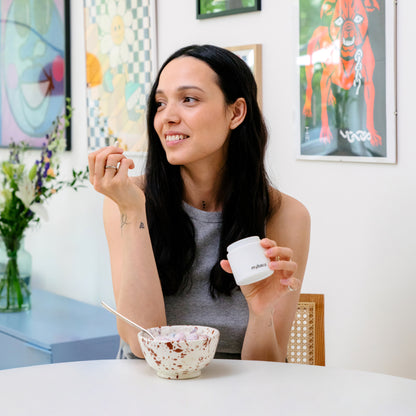Dietbacs® Probiotikum – Frau nimmt eine Kapsel während des Frühstücks ein.